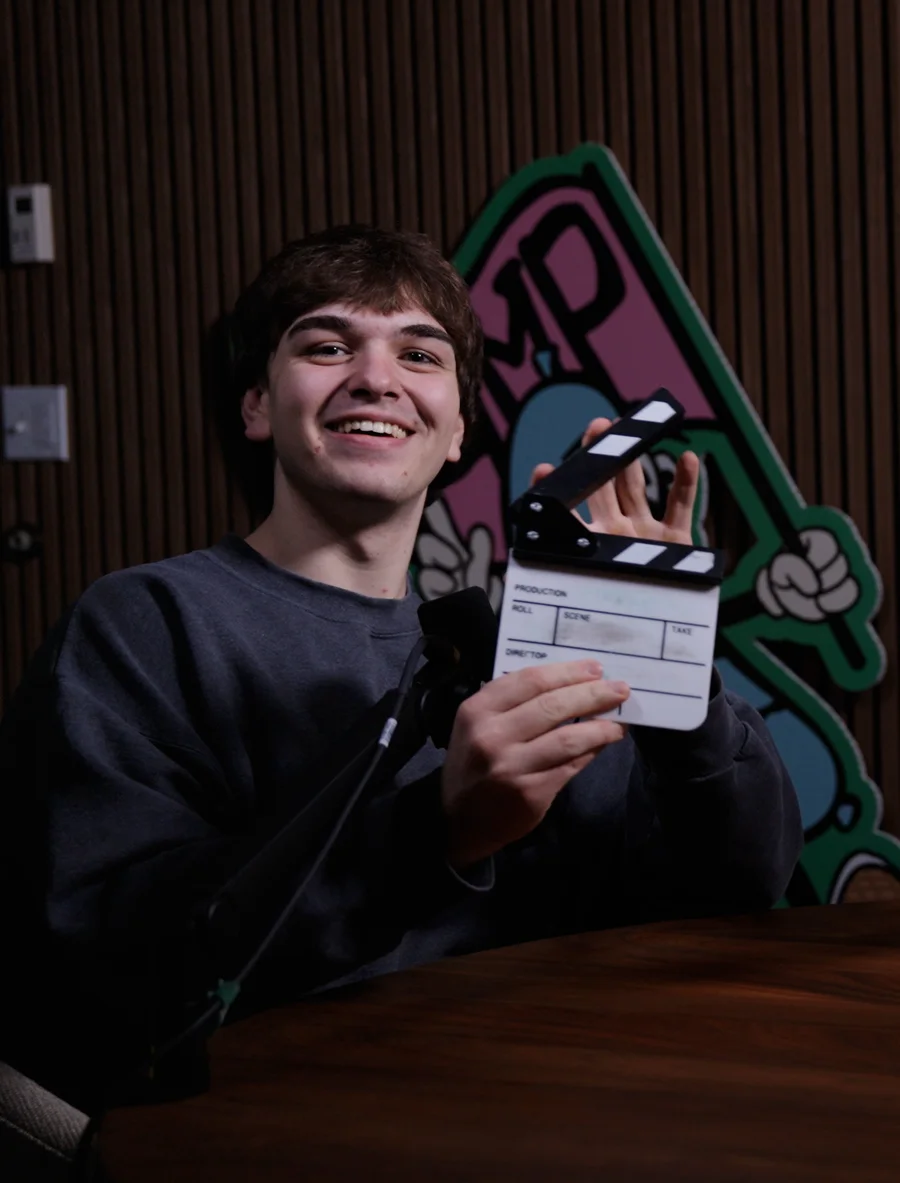 Blake holding a clapperboard on the Trifilm podcast set